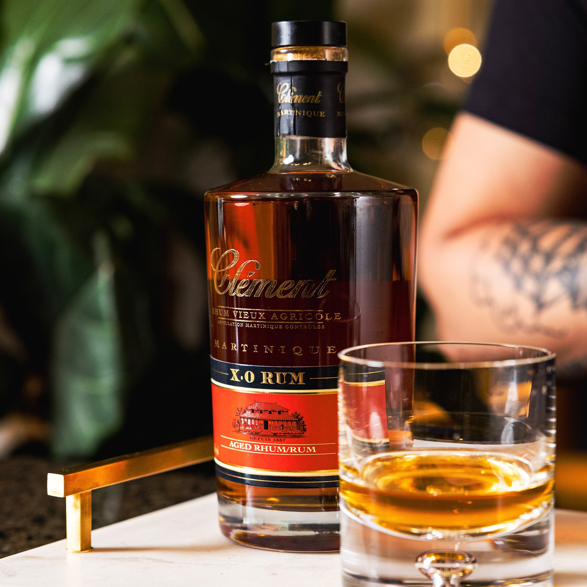 Bottle of Cément X.O rum with a glass of rum on a table.