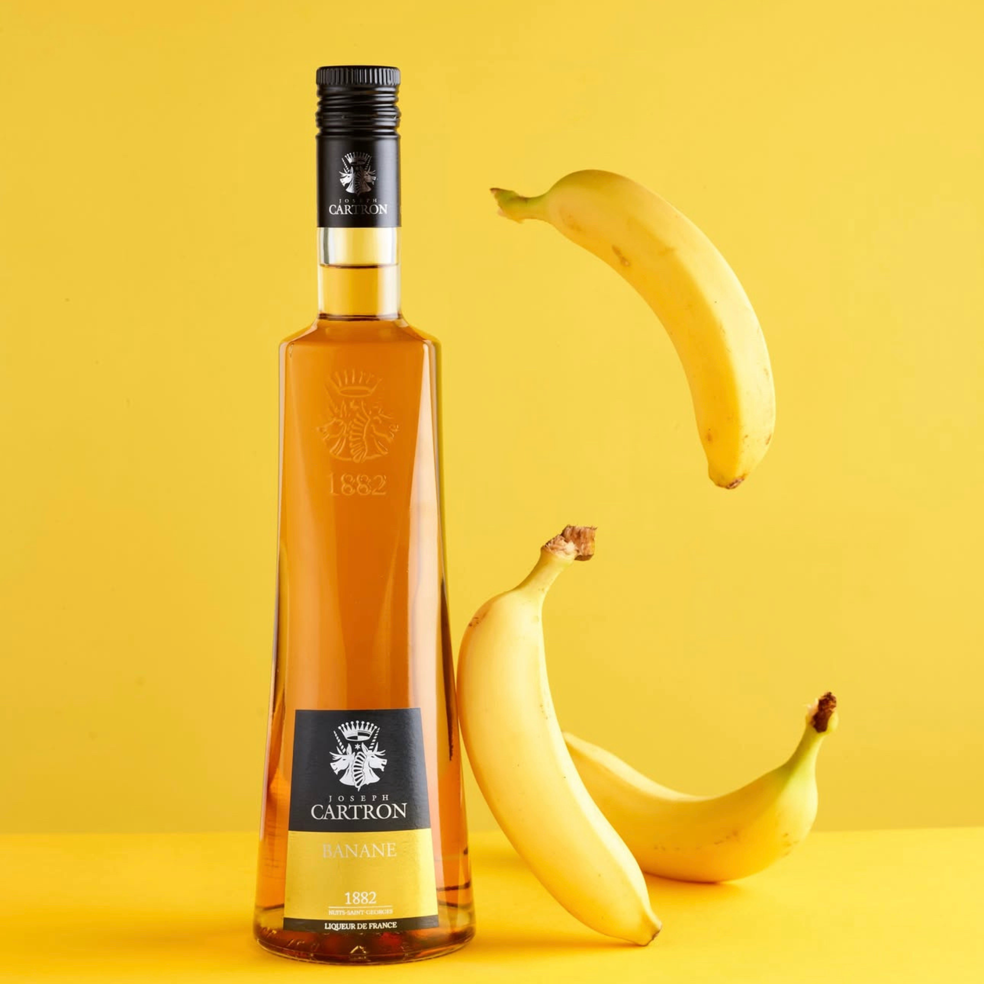 Bottle of Cartron rum with bananas on a yellow background