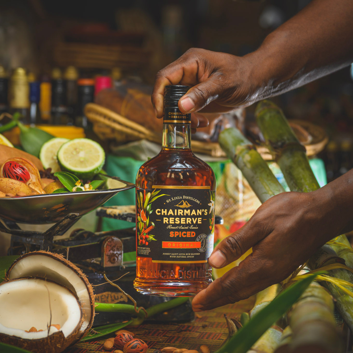 Bottle of Chairman's Reserve Spiced rum held by a hand with a tropical setting in the background.