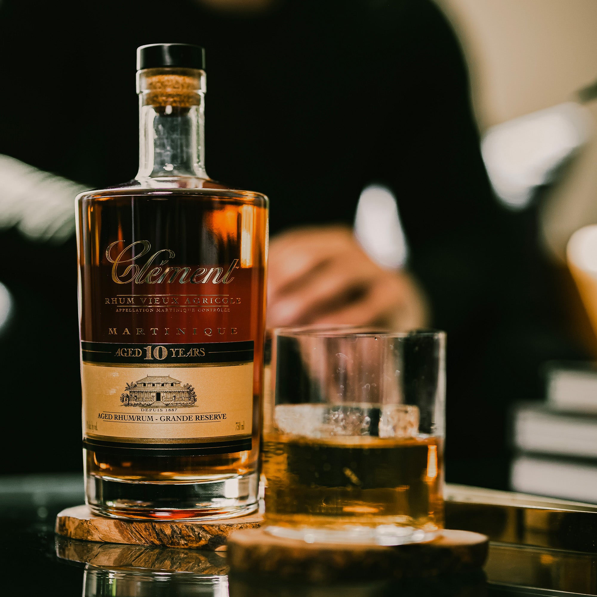 Bottle of Clement 10 year rum with a glass on a wooden coaster