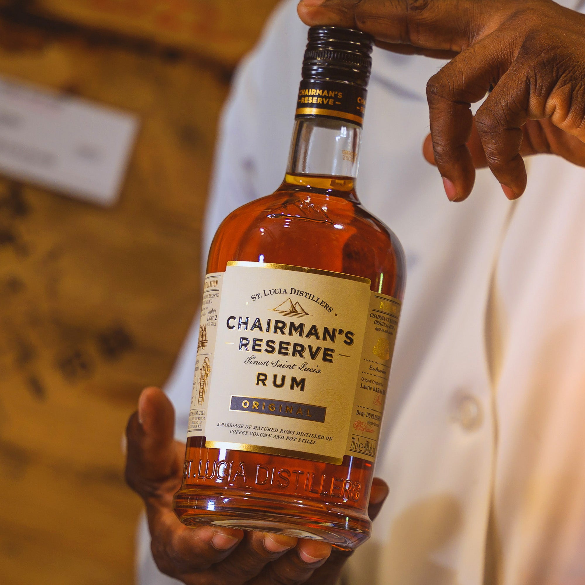Bottle of Chairman's Reserve Rum held by a person with a blurred background
