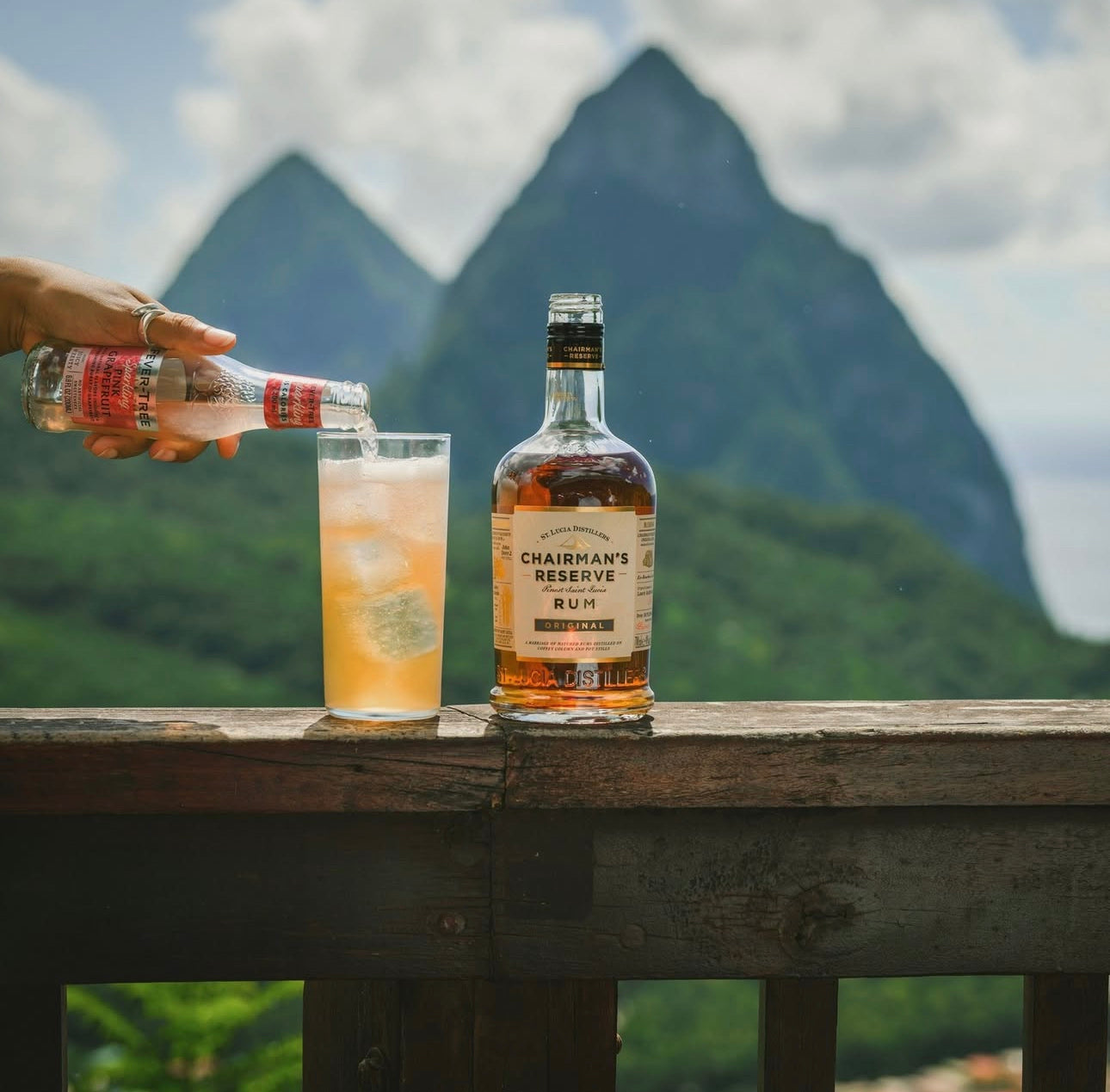 Chairman's Reserve rum bottle with a glass of cocktail on a wooden table against a mountainous background