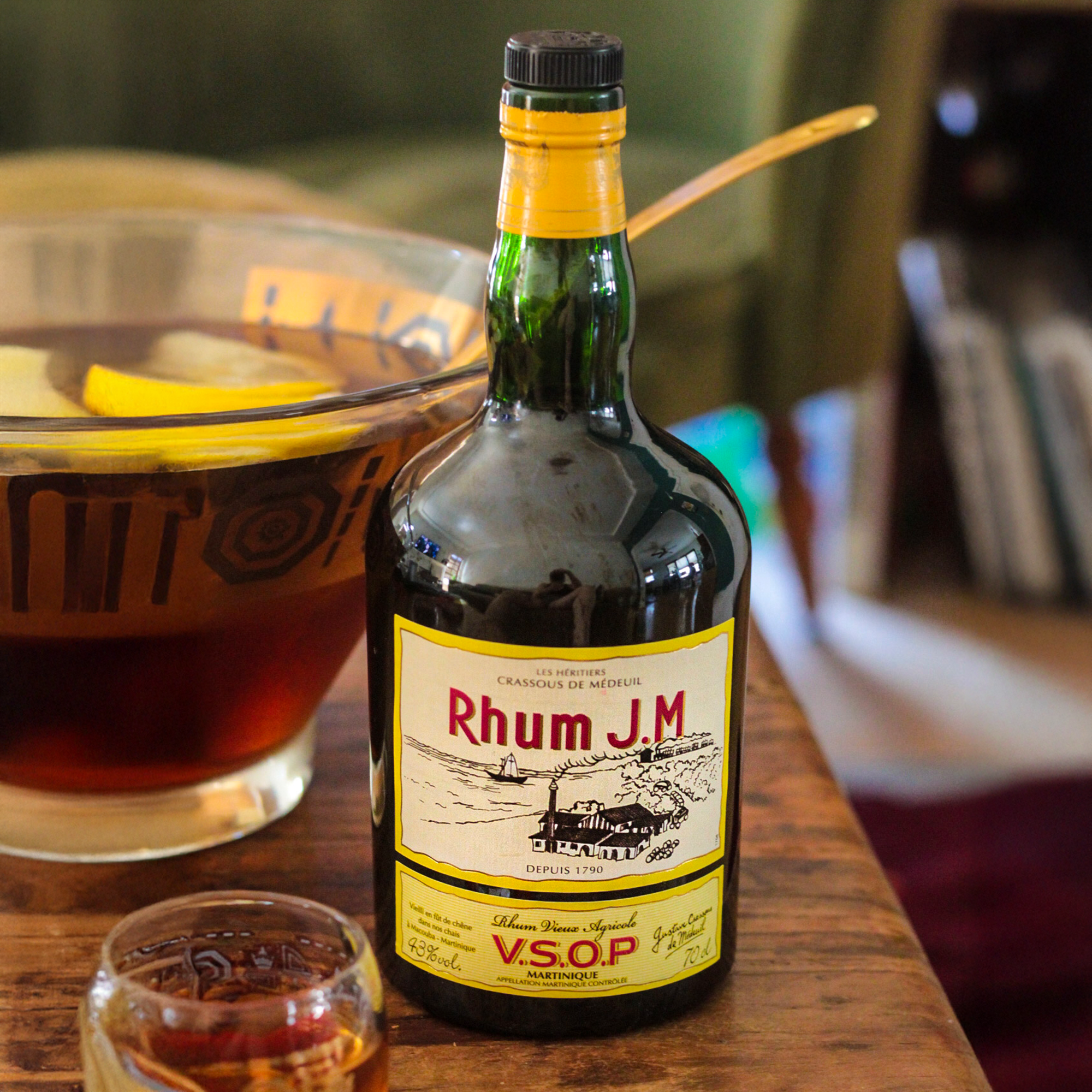 Bottle of Rhum J.M VSOP with a glass of rum on a wooden surface