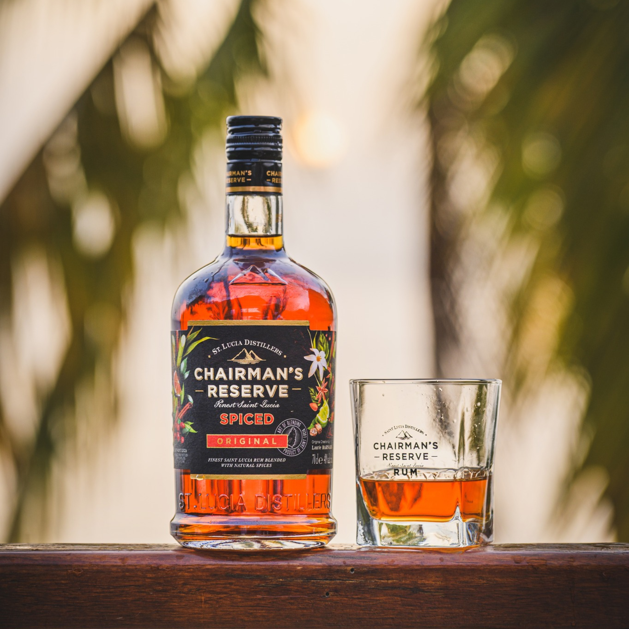 Chairman's Reserve Spiced rum bottle and glass on a wooden surface with blurred natural background