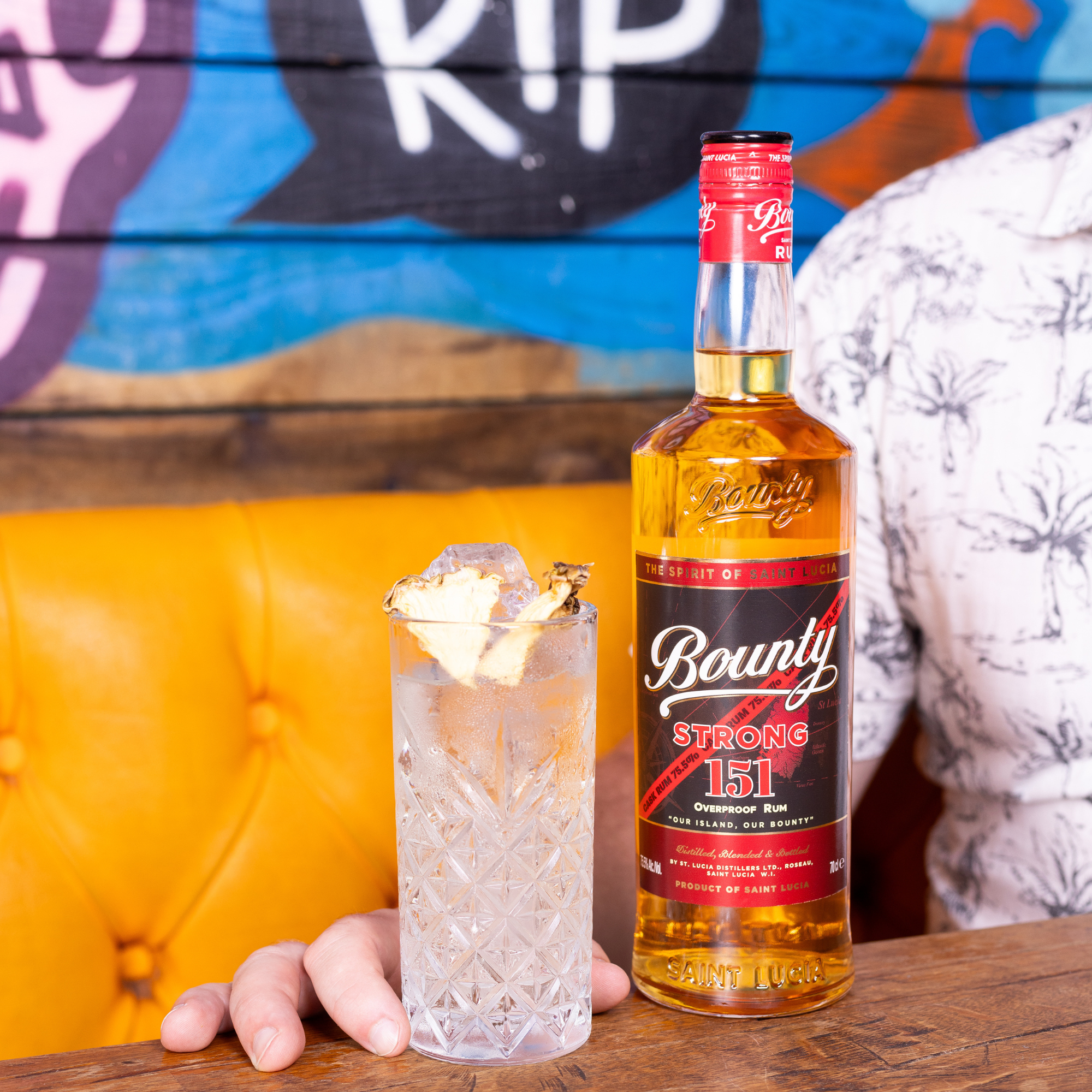 Bounty Strong 151 bottle with a cocktail on a wooden surface against a colorful wall.