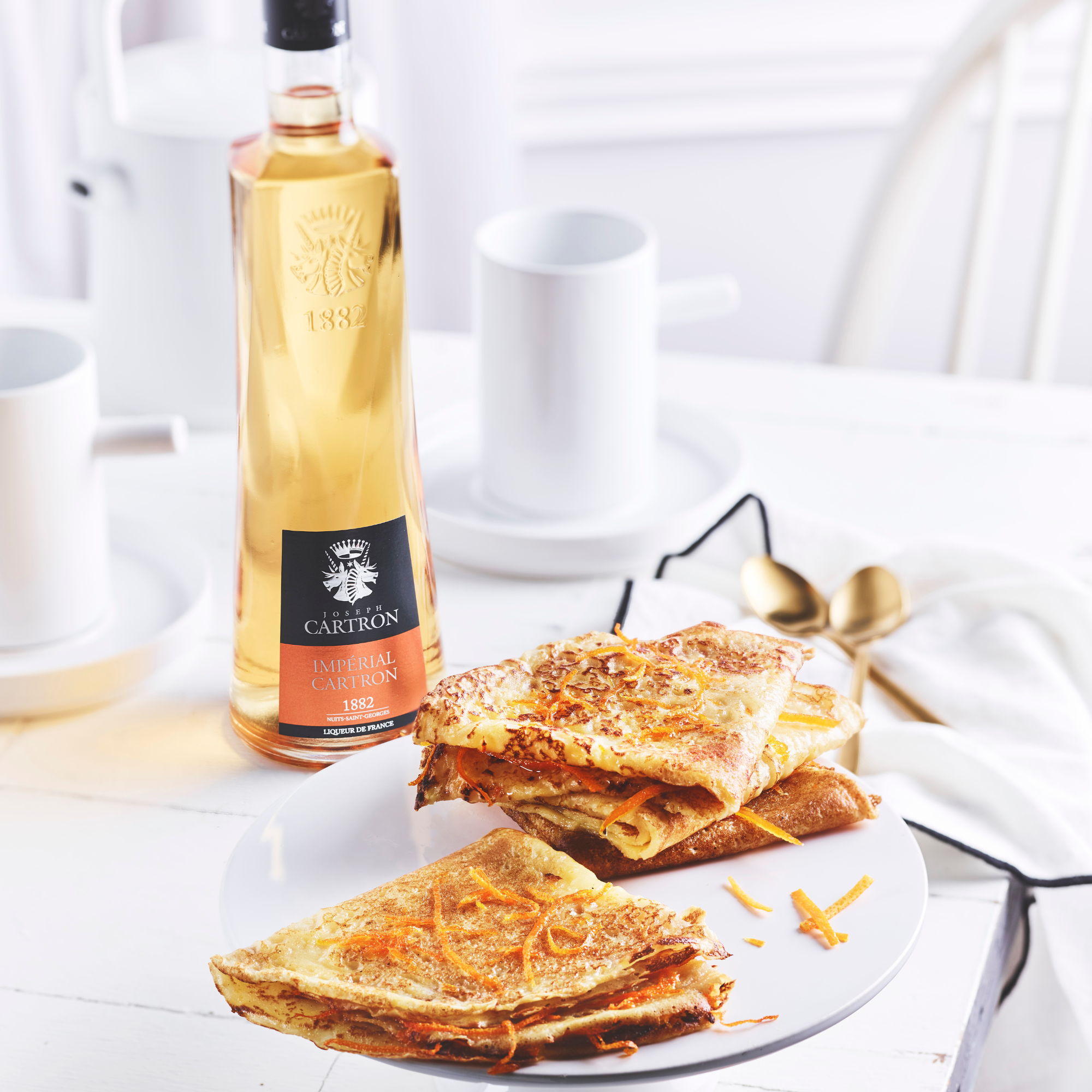 Stack of crepes on a plate with a bottle of Armagnac in the background