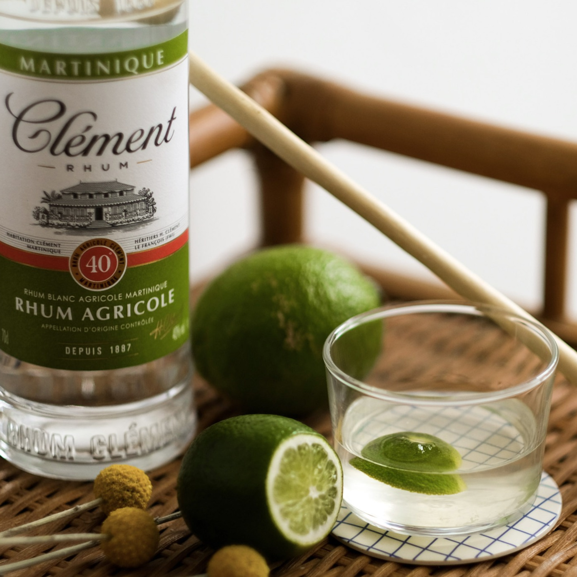 Bottle of Clément rhum agricole with a glass of lime juice on a wooden surface.