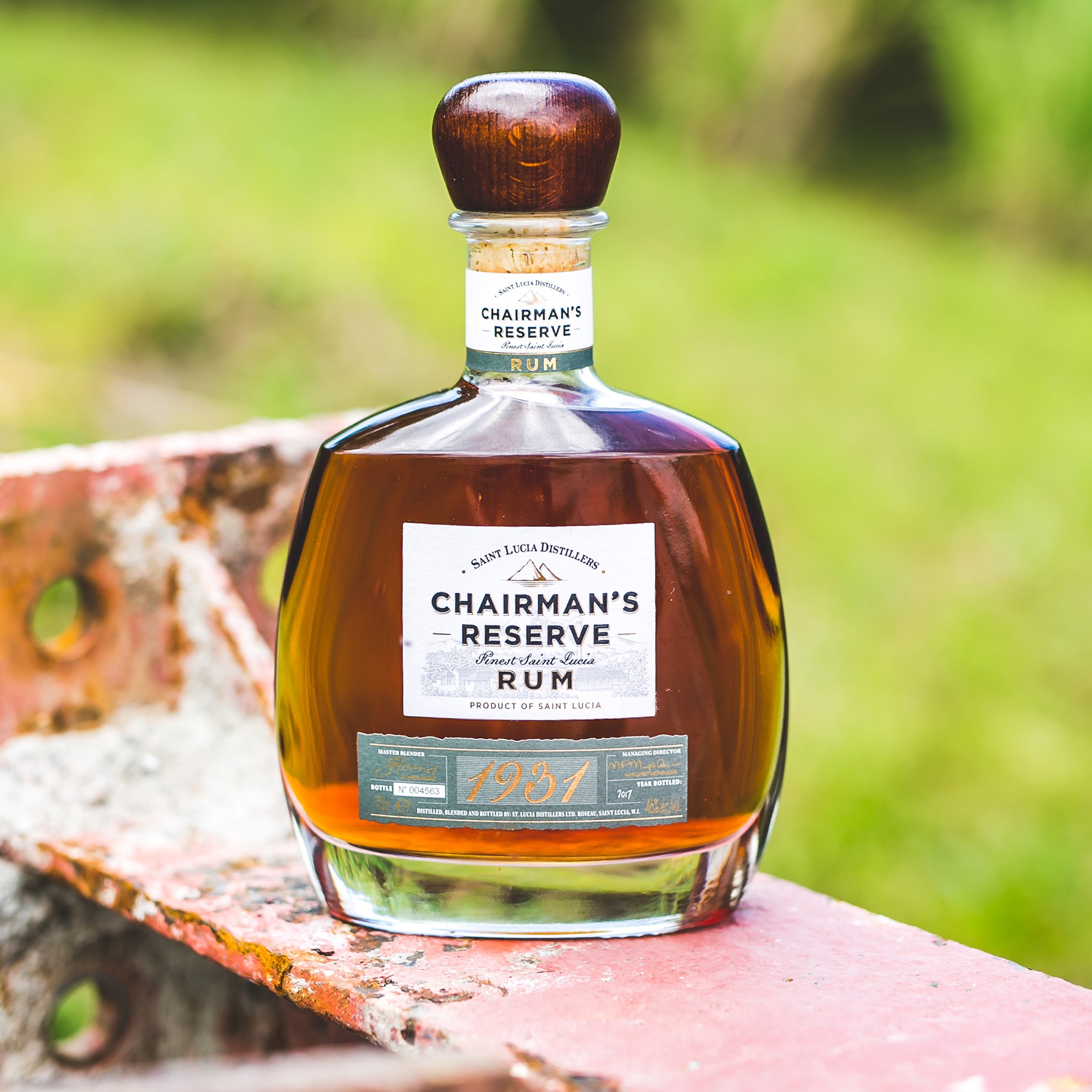 Bottle of Chairman's Reserve Rum 1931 on a wooden surface with a blurred green background