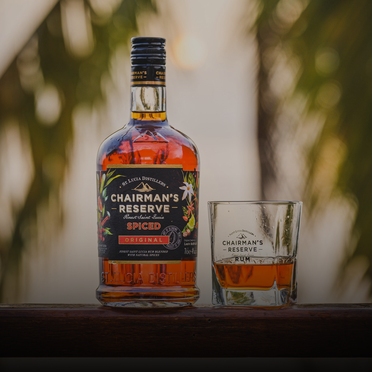 Chairman's Reserve Spiced rum bottle with a glass of rum on a wooden surface.
