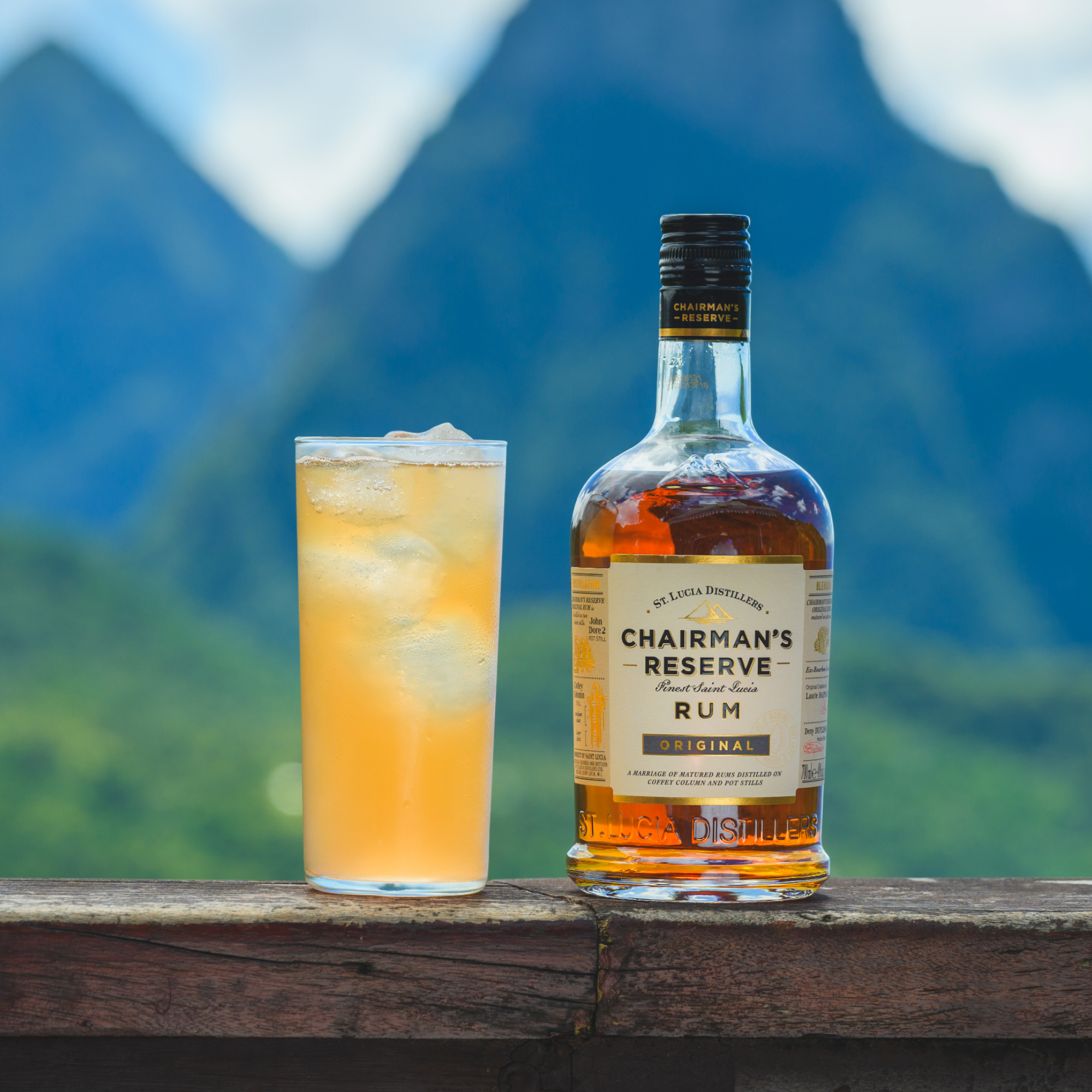 Chairman's Reserve Rum bottle with a cocktail on a wooden surface against a mountainous background