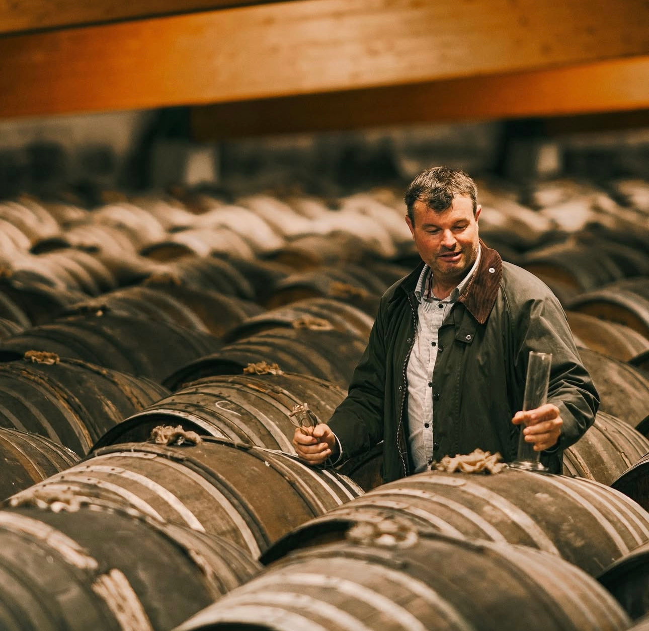 Man inspecting  barrels in a cellar
