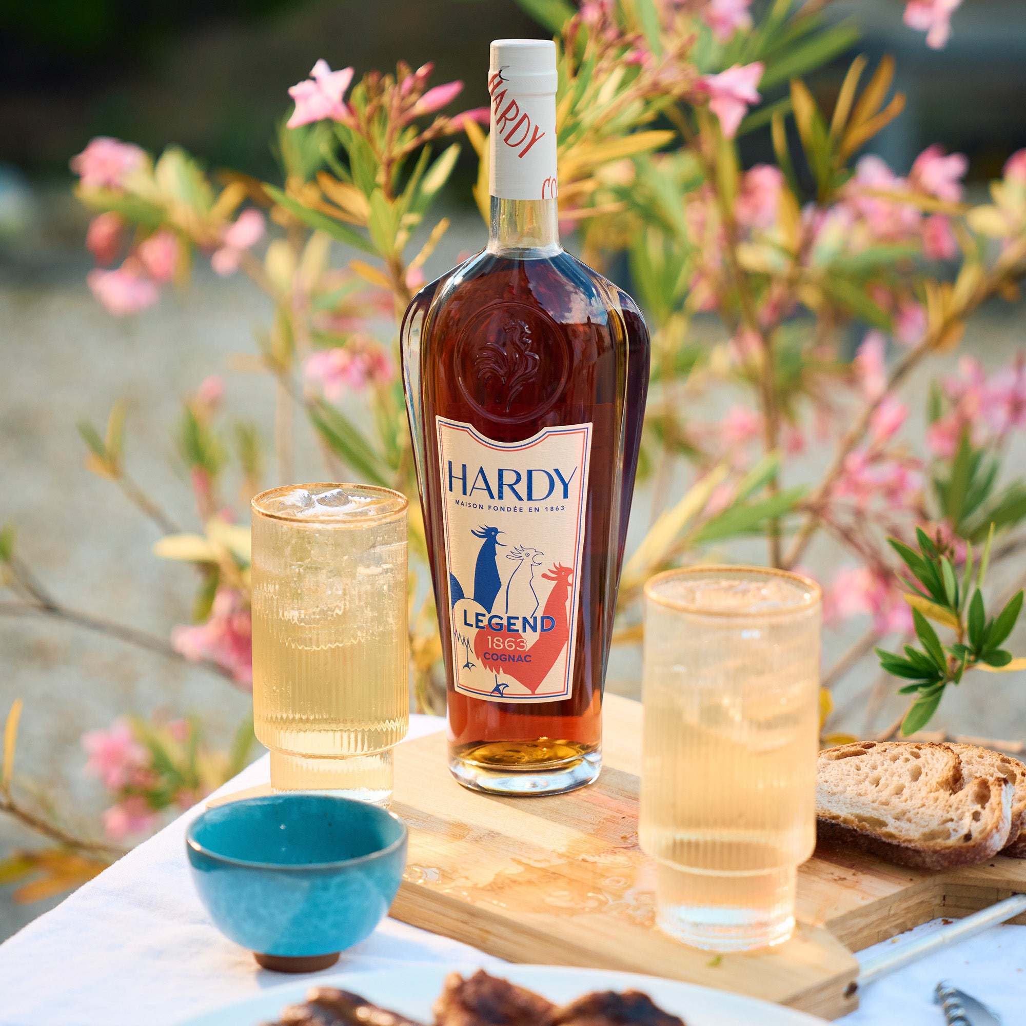Hardy Legend bottle with two glasses and bread on a table outdoors