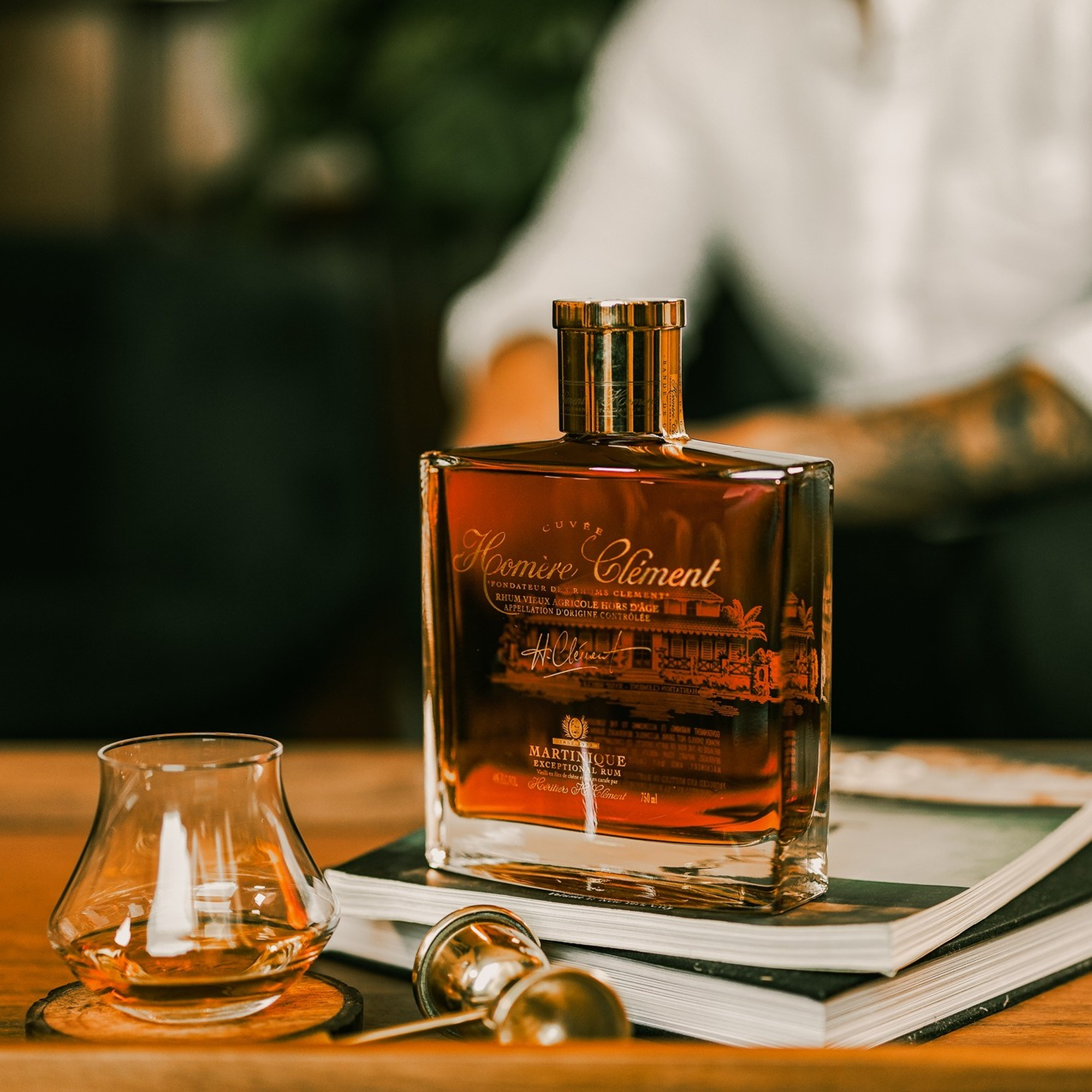 Bottle of Clément Homere with a glass on a wooden surface