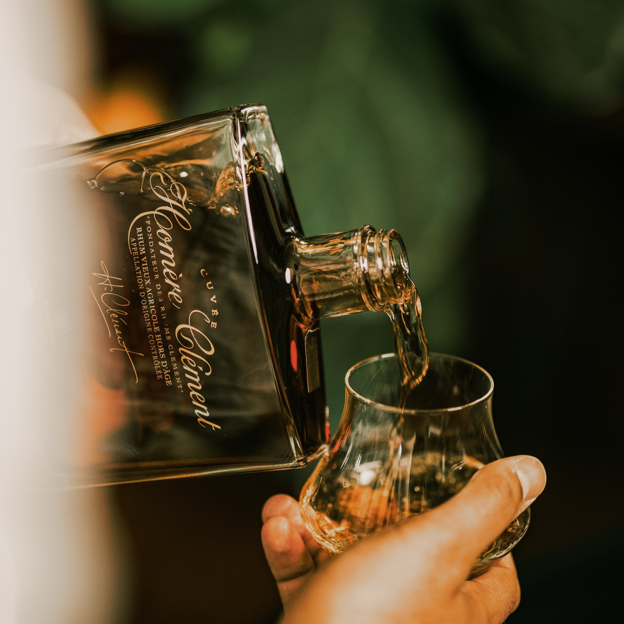Bottle of Clement Homere being poured into a glass with a blurred background